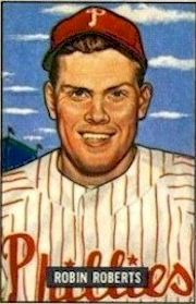A baseball card image if a smiling man wearinga white baseball jersey with red pinstripes and a red baseball cap; the caption on the card reads "Robin Roberts"
