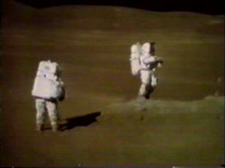 TV camera still of Duke (left) and Young on the rim of Plum. Duke remarked at this time, "John, you are just beautiful. That is the most beautiful sight." Young is standing next to a boulder from which sample 61295 was taken.