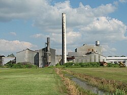 A row of large corrugated metal buildings with a large smokestack reading "CINCLARE".