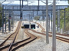 Long shot view of a dual track railway with two tracks diverging in the middle and entering a tunnel between the two tracks