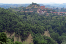 Village with orange roofs are surrounded by rocks and trees.