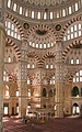 The interior of the mosque showing the symmetry of the mosque, the intricate artwork and calligraphy, and the decorative ablaq in the arches