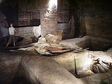Cave with pits to contain tanning liquor for preserving leather in floor