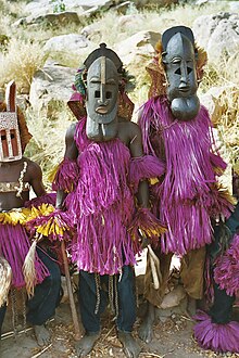 Two men donning Dogon ceremonial masks with pink costumes during a masquerade in Mali.