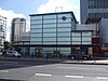 A light blue building with a dark blue sign reading "ELEPHANT & CASTLE STATION" in white letters all under a blue sky with white clouds