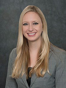 (Image of half-length portrait of young, blonde woman in business suit, smiling at the camera)