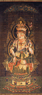 Deity embellished with ornaments seated on a pedestal.