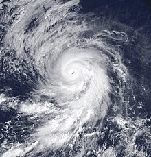 A satellite image of a powerful hurricane over the Eastern Pacific Ocean; it has a well-defined eye surrounded by thick, intense convection, with pronounced spiral bands extending southward from the storm and multiple arcs of thin high clouds fanning out to the northwest