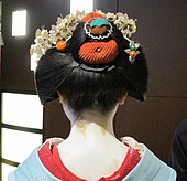 A maiko wearing a blue kimono viewed from the back.