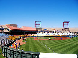 A green baseball field surrounded by a seating bowl with red, yellow, and blue seats