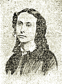 Poor quality B&W portrait photo of a young woman wearing a dark blouse, her hair in long ringlets.