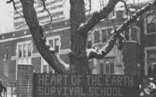 Sign in front of tree in front of brick school in winter