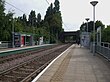 A set of two tram tracks between two platforms with shelters.