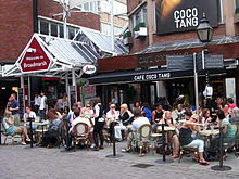 Outdoor tables with seated customers near to former shopping centre entrance