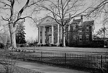 Black and white photo shows a white-columned mansion.