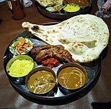 L-25 Description: an Indian meal of chicken curry, shrimp curry, naan, papad, tandoori chicken, saffron rice, and salad.