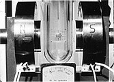 A tin cylinder—in a Dewar flask filled with liquid helium—has been placed between the poles of an electromagnet. The magnetic field is about 8 millitesla (80 G).