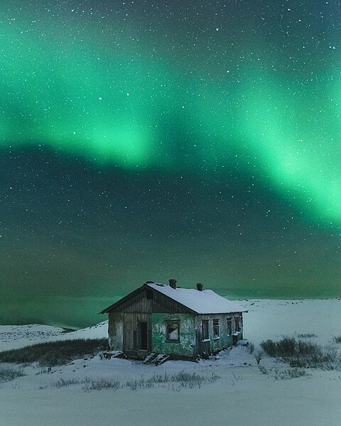 图为笼罩在捷里别尔卡废弃天气观测站上的北极光。