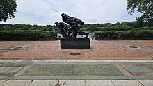 A color photograph of a dark sculpture on a brick terrace