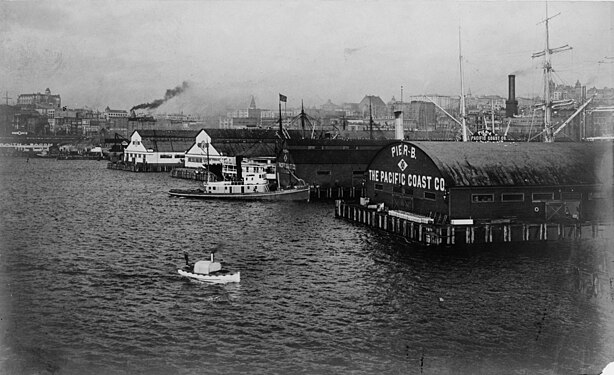 Dated 1904 by the Library of Congress. Clearly the "new" piers (although Pier C is not visible). From left to right, Piers 2, 1, A, B. NOTE the radically different shape of Pier A shed compared to before. Pier B is not as dramatically different, but the configuration of doors and windows is entirely different and there is no smaller shed on the side. Written on Pier A shed: "Pier A", the Maltese Cross symbol of the Pacific Coast Company, "[The] Pacific Coast Co.". Written on Pier B shed: "Pier B", the Maltese Cross symbol of the Pacific Coast Company, "[The] Pacific Coast Co.". It's imaginable that Pier B could still be the same structure as before, but unlikely because we'd almost certainly see the transverse sheds and because of the maps above. So presumably by this time the transverse sheds are gone. Of course, there is no clear reason to believe the 1904 date to be precise.