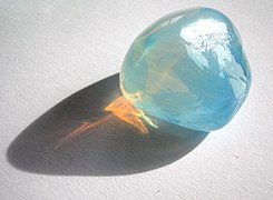 Tyndall effect in an opalite: it scatters blue light making it appear blue from the side, but orange light shines through. opal is a gel in which water is dispersed in silica crystals
