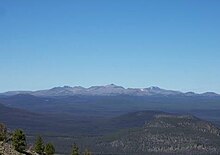 A large gently-sloped mountain rising above the surrounding area on a clear day