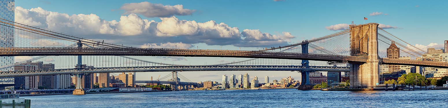 Brooklyn Bridge, Manhattan Bridge, Williamsburg Bridge, and a "cloud bridge" right before Manhattan skyscrapers cast the scene into shadow during sunset.
