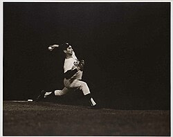 a baseball pitcher on the mound and in full-stride, throwing towards homeplate