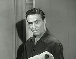 A dark-haired man wearing a dark shirt