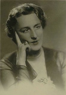 Black and white photograph of a middle-aged woman with short hair with her right hand resting on her face.