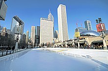 An empty ice skating rink with tall buildings in the background