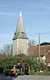 A shingled broach spire on a flint tower