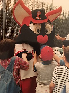 A person in an anthropomorphic bat costume greeting children at a ballgame