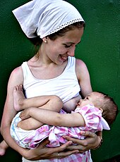 smiling mother holds baby to breastfeed