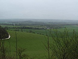 View of rolling agricultural fields and hedgerows under an overcast sky