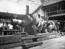 Finishing the ends of a crankshaft after building;[117] an improvised lathe for machining a large steam engine crankshaft, 1900[78] with a worm and wheel for turning the shaft in the centre. In the background on the far right is a screw cutting machine.[118]