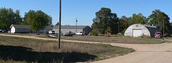 House and two metal buildings; two cars and two pickups parked near house; truck parked near Quonset hut