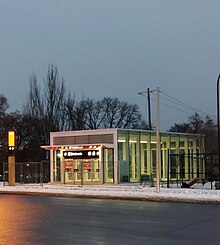 Photo of a glass panelled station entrance with orange accenting