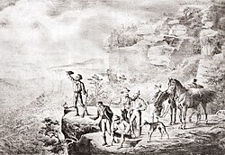 Image shows the group of explorers standing at the edge of a cliff, looking out over plains.