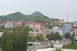 View of North Mitrovica; Zvečan Fortress on the mountain to the left, Trepča chimney on the right, and Ibar Bridge in the center.
