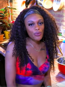 Bae stands at a kitchen counter with a red bowl demonstrating how to make a spiritual bath.