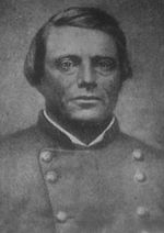 Photo shows a clean-shaven man with a broad face wearing a gray uniform with two rows of buttons.
