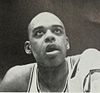 Portrait of Walt Hazzard in 1964 wearing a jersey and peering up to his left with mouth agape.