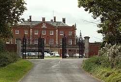 A large red brick building behind black iron gates.