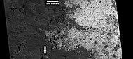 HiWish计划下高分辨率成像科学设备放大显示的苏志陨击坑中的浅色岩层，箭头指向一座含有浅色物质的小陨坑。