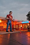 Gus's Giant Muffler Man, in front of a restaurant, with neons lit, dusk