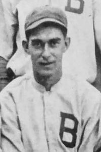 A man win a light baseball uniform with a dark "B" on the chest.