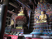 Ming dynasty statues of Vairocana (center), flanked on the far left by Amitabha and on the right by Bhaisajyaguru. Projecting tongues from Vairocana's throne are petals that symbolize his radiance in infinite directions.