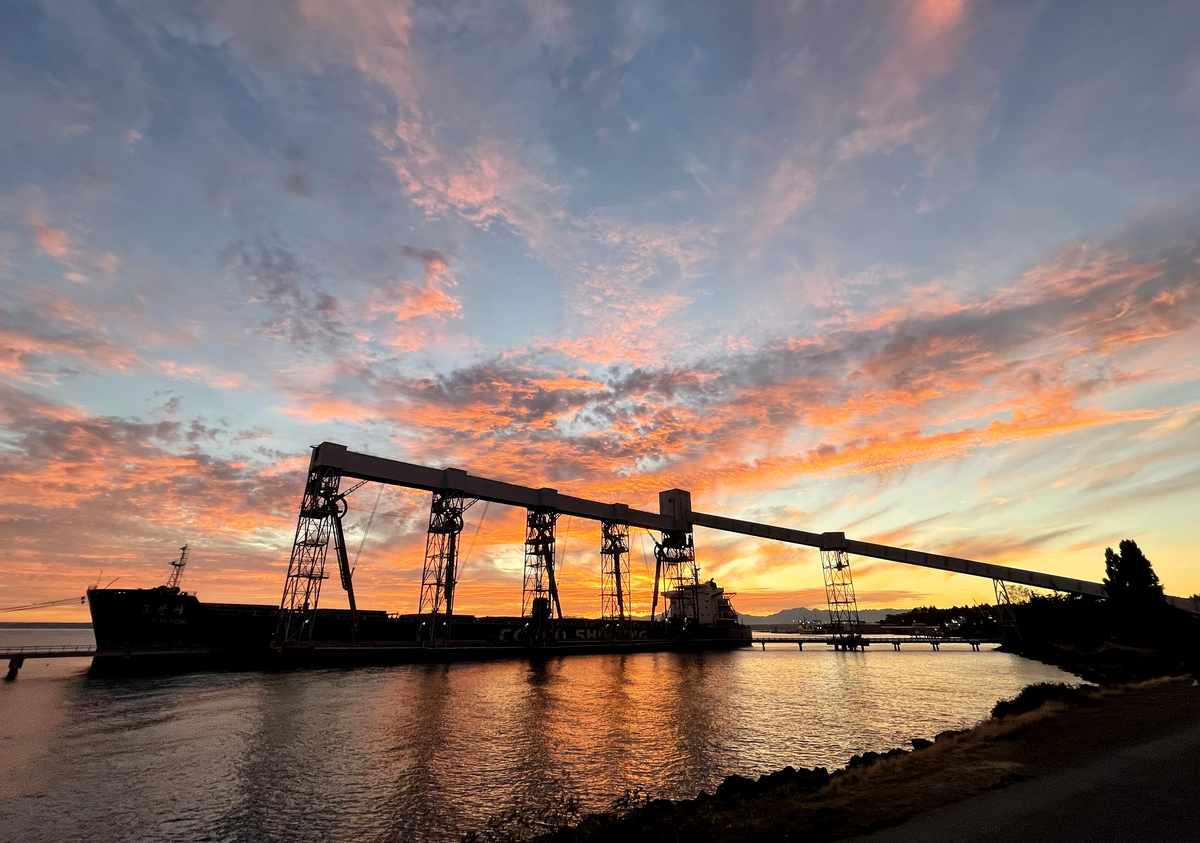 Seattle's Pier 86 grain terminal and bulk carrier ship Ji Xian Feng, silhouetted at sunset, evening, September 24, 2021