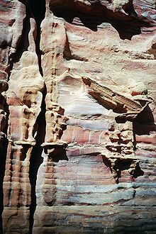 Photographie d'un ancien monument sculpté dans la roche. Le monument est dégradé par les intempéries et donne l』impression de se fondre dans la roche.